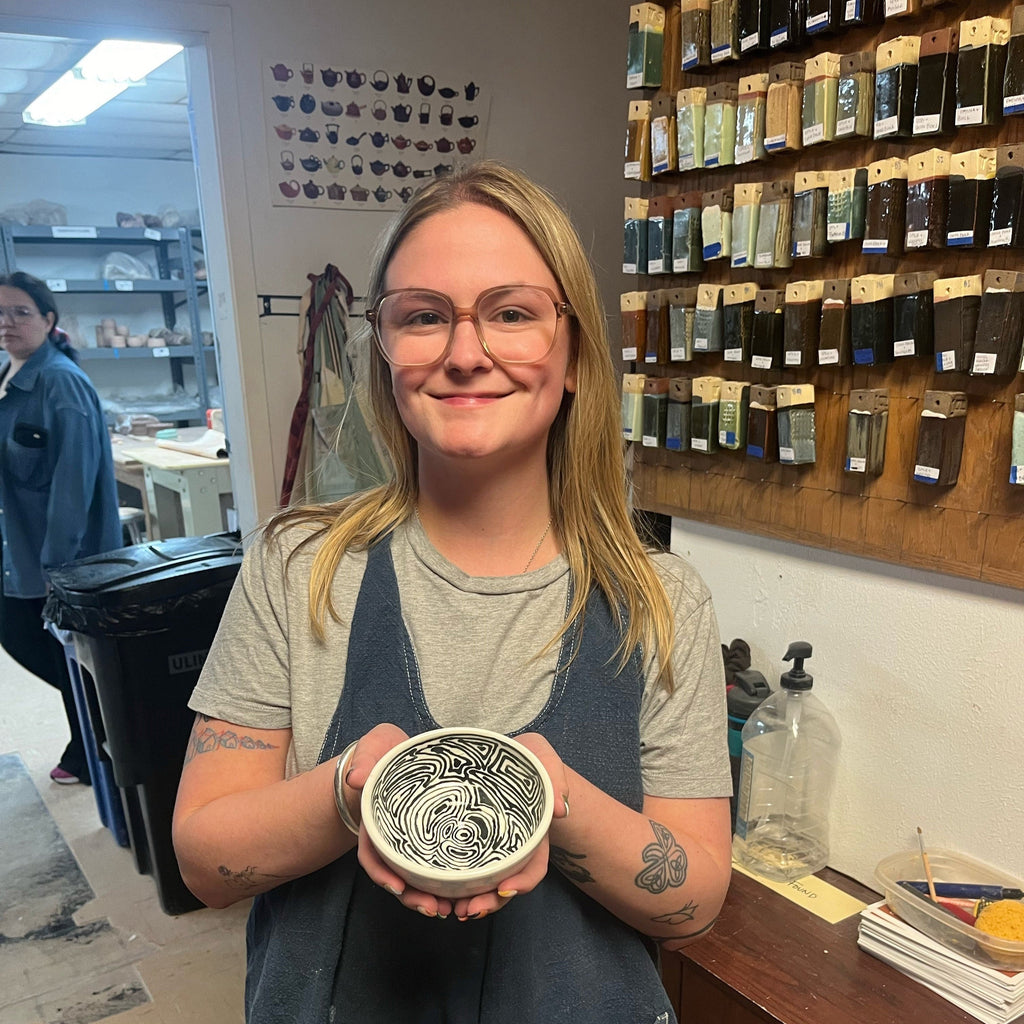 Student holding ceramic bowl with sgraffito design created in pottery wheel clay ceramics classes for adults at the Creative Arts Center of Dallas. 